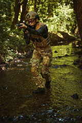 Woman in helmet standing in forest and holding gun in hands