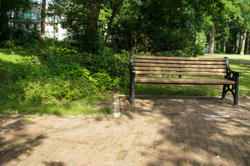 Brown wooden bench in a shady spot in the park in the Netherlands