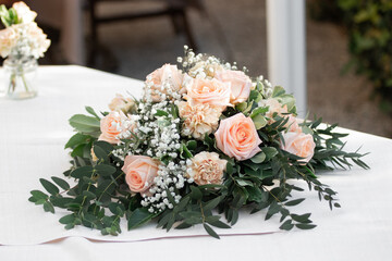 Pink rose wedding bouquet on the white table in the summer day.