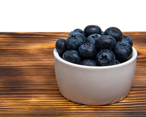 Fresh blueberry in white dish on wooden background
