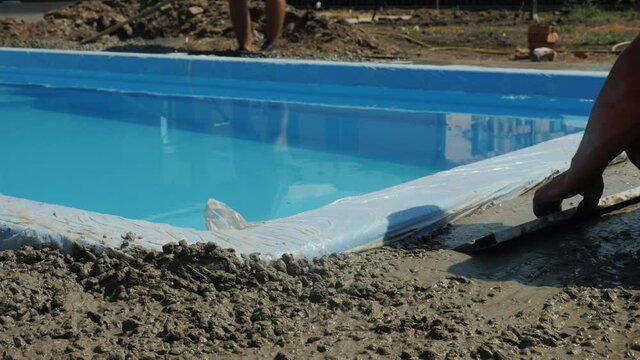 Builders pour concrete around the pool, do paving.