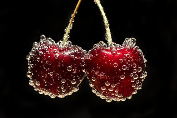 Isolated red cherries in sparkling water with black background