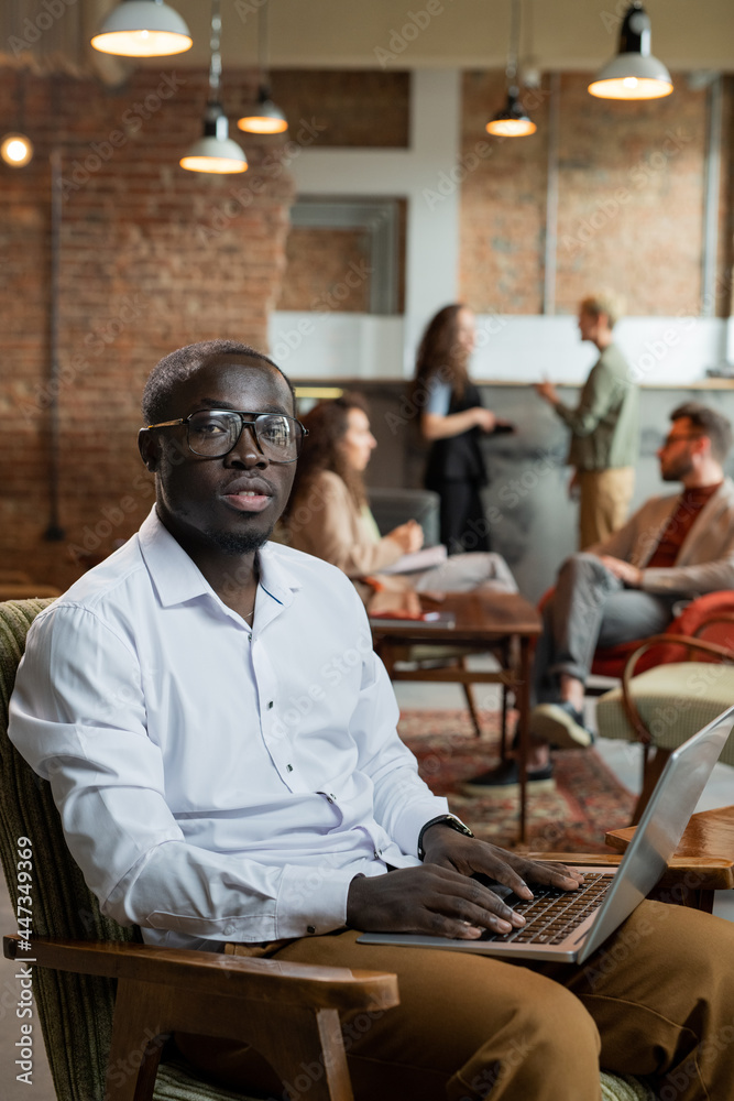 Aufkleber Young businessman working in the net while his colleagues discussing working points on background