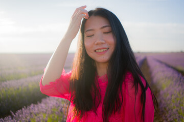 young Asian woman outdoors at lavender flowers field - happy and beautiful Korean girl in sweet Summer magenta dress enjoying holidays relaxed on purple floral meadow