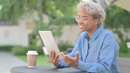 African Woman Doing Video Chat on Tablet in Outdoor Cafe 