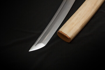 Tanto blade in shirasaya scabbard on black background.