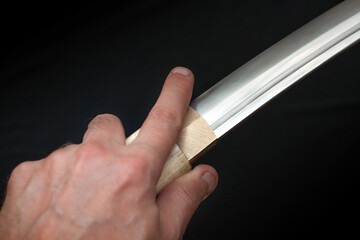 Tanto blade in shirasaya scabbard on black background.
