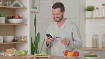 Man Doing Online Shopping on Smartphone in Kitchen