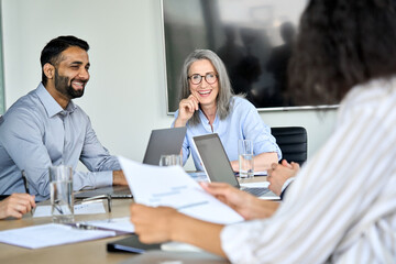 Senior female ceo and happy multicultural business people discussing company presentation at...