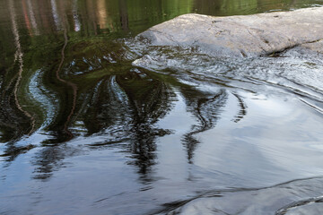 Obraz premium Stream water goes over wet gray rock. Ruskeala