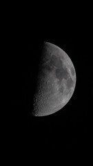 Waning half moon close up - black sky background. 