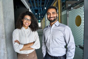 Two happy diverse professional executive business team people African American woman and Indian man looking at camera standing in office lobby hall. Multicultural company managers team portrait. - Powered by Adobe