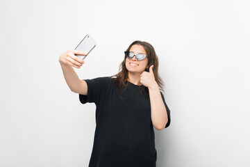 Naklejka premium A nice photo of a young woman taking a selfie with sun glasses on while holding a thumb up smiling