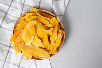 Natural organic dried ripe mango slices on wooden bowl, light background. Dehydrated candied fruit-...