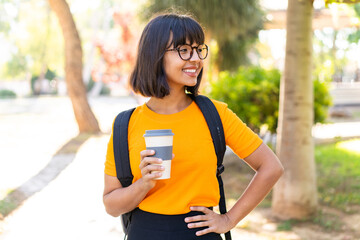 Young student woman in a park holding a take away coffee