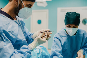 Medical doctors preparing surgical equipment for operation inside private clinic - Focus on male...
