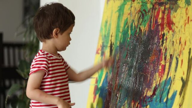 Little boy draw and art with brush and paints at home