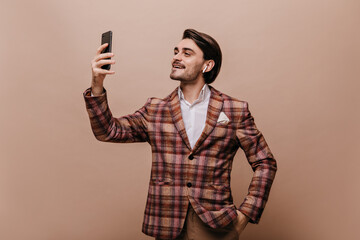 Handsome young man with brunette hair and bristle, white shirt and brown plaid blazer, wearing...