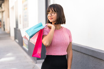 Young brunette woman in the city holding shopping bags and a mobile phone