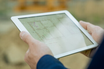Close-up of engineer examining blueprint of future project online on digital tablet