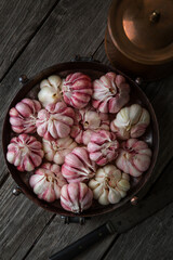 A lot of fresh garlic in a bowl on an old wooden background, harvesting