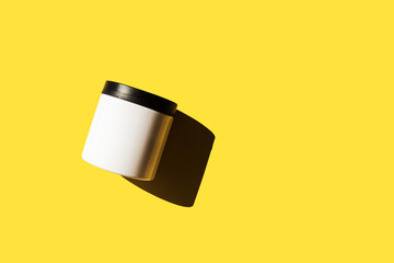 Advertising isolated container on bright sunny yellow background. Skincare, bodycare beauty product in plastic pot package concept. White unbranded, balsam, hand or face creme jar mockup