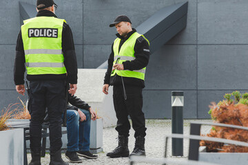 Two police officers talking to man on the street - obrazy, fototapety, plakaty