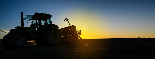 Farmer with tractor equipment on field by sunset Harvest equipment. 