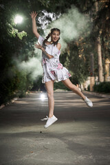 Happy teenage girl in floral dress jumping in the park