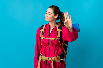 Young mountaineer woman over isolated blue background making stop gesture and disappointed