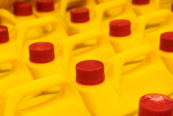 Yellow Plastic bottles cans Yellow household chemicals Liquid Refill in the hardware warehouse store. Stack of Canisters with red plastic cork cap.