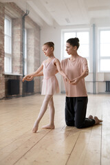 Trainer adjusting hand position of little ballerina