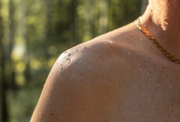 Male shoulder with water drops on suntanned skin of caucasian man with gold chain on neck. Wet...