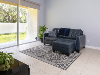 Navy blue love seat and ottoman by large sliding door.