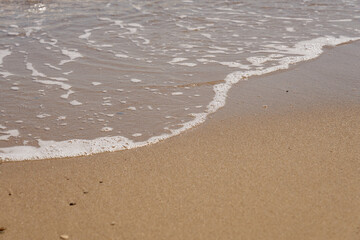 Fototapeta na wymiar Tropical sandy beach with waves and foam.