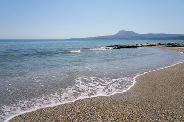 Waves with foam on Aegean sea coast in Crete Greece.