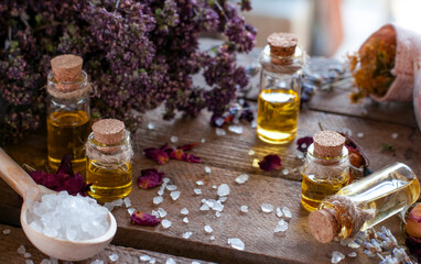 essential oil bottles with dry ingredients of rose, lavender  and white crystals in the spoon on...