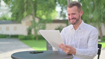 Mature Adult Man Celebrating Success While Reading Documents 