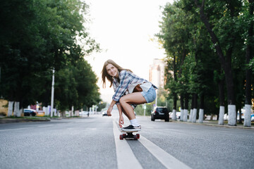 Euphoric happy woman riding on a skateboard on an empty city road in morning