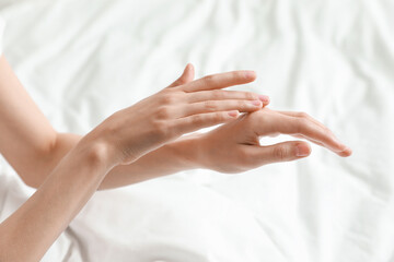 Obraz na płótnie Canvas Woman applying hand cream in bed, closeup