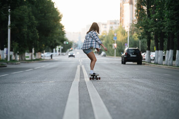 Agile woman riding on a skateboard on an empty city road in the morning