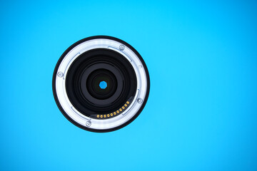 Lens of a full-frame mirrorless camera with electrical contacts for lens data; blue background and...
