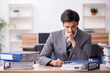 Naklejka premium Young male employee unhappy with excessive work in the office