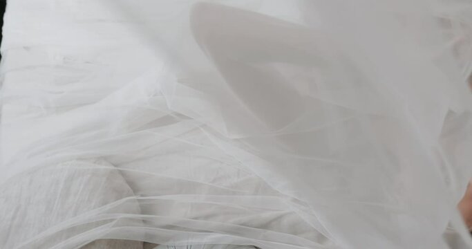 Bride in wedding dress in the morning. Lies on the bed and gently touches the tulle with her hands. Concept happy bride, wedding morning, dress, newly weds.