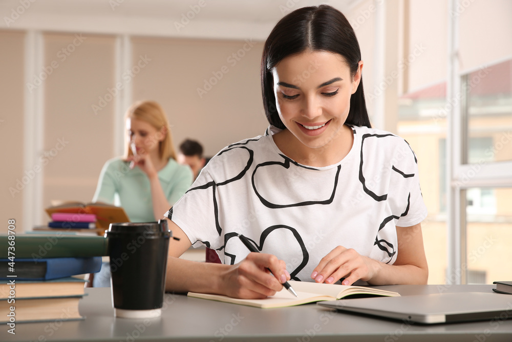 Poster young woman studying at table in library