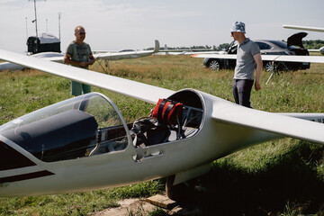 Soaring club, getting ready for the flight on glider airplane. Small aviation sport. Two man checking cabin instrument panel of vintage airplane