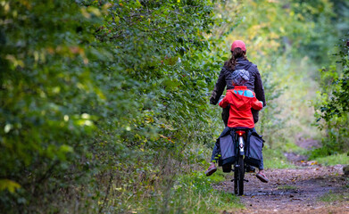 

a woman with a child on a bicycle in the forest