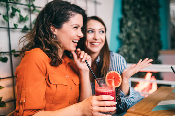 Friends enjoying together in restaurant. They are drinking a fresh beetroot and orange juice.