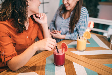 Friends enjoying together in restaurant. They are drinking a fresh beetroot and orange juice.