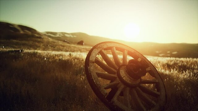 Old wooden wheel on the hill at sunset